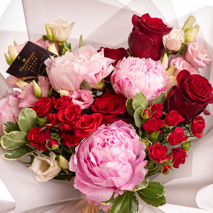 Detaliu de aproape cu florile din Buchet bujori si trandafiri rosii, varianta Deluxe, compus din 4 bujori roz, 2 flori de lisianthus roz, 3 crengute de pittosporum, 2 trandafiri ramificati rosii, 4 trandafiri rosii