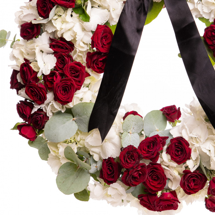 Coroana funerara deosebita din flori naturale cu hortensii albe si trandafiri rosii, pe un fundal alb, detaliu