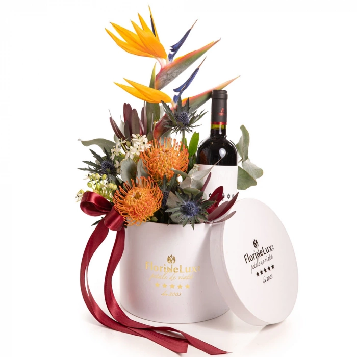 Vedere de ansamblu a produsului Aranjament flori exotice, varianta Standard, compus din 1 sticla de vin Feteasca Neagra Corcova, 2 flori de strelitzia, 2 flori de leucospermum, 2 flori de ornitogalum, 2 crengute de leucadendron, 1 floare de eryngium si 2 crengute de eucalipt.