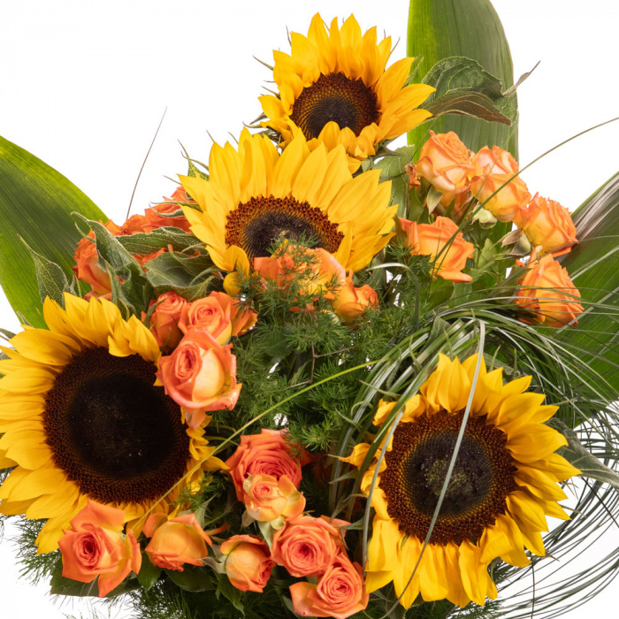 Detaliu de aproape cu florile din Buchet cu floarea-soarelui Orange Summer, varianta Deluxe, compusa din 4 flori de floarea-soarelui, 3 crengute de asparagus umbelatus, 10 fire de beargrass, 4 frunze de aspidistra, 4 trandafiri ramificati portocalii
