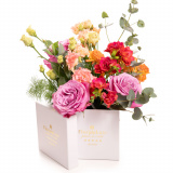 Vedere de ansamblu a produsului Cutie cu flori colorate, varianta Deluxe, compusa din 3 trandafiri mov, 1 asparagus umbelatus, 1 crenguta de eucalipt, 1 trandafir ramificat portocaliu, 3 frezii cyclam si 2 lisianthus somon
