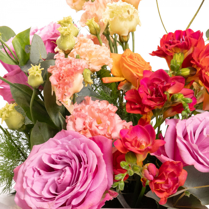 Detaliu de aproape cu florile din Cutie cu flori colorate, varianta Deluxe, compusa din 3 trandafiri mov, 1 asparagus umbelatus, 1 crenguta de eucalipt, 1 trandafir ramificat portocaliu, 3 frezii cyclam si 2 lisianthus somon