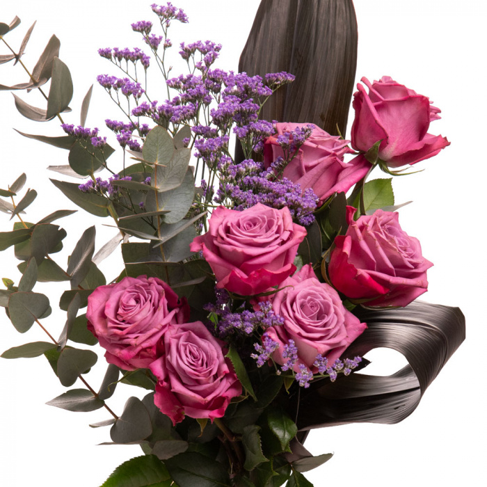Detaliu de aproape cu florile din Buchet cu trandafiri Purple Dream, varianta Deluxe, compus/a din 7 trandafiri mov, 2 frunze de cordiline, 2 fire de limonium, 3 crengute de eucalipt