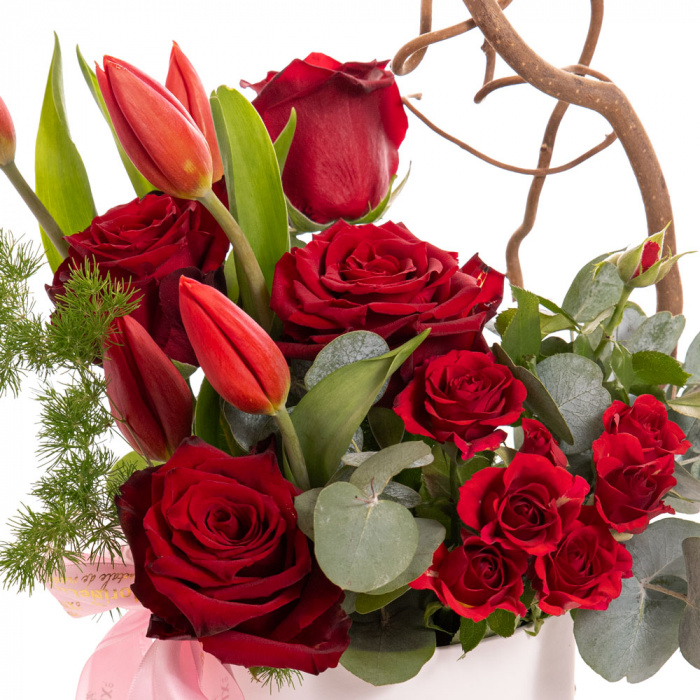 Detaliu de aproape cu florile din Aranjament trandafiri si lalele rosii, varianta Deluxe, compus din 1 crenguta de corylus, 1 crenguta de asparagus umbelatus, 1 crenguta de eucalipt, 5 lalele rosii, 4 trandafiri rosii si 1 trandafir ramificat rosu