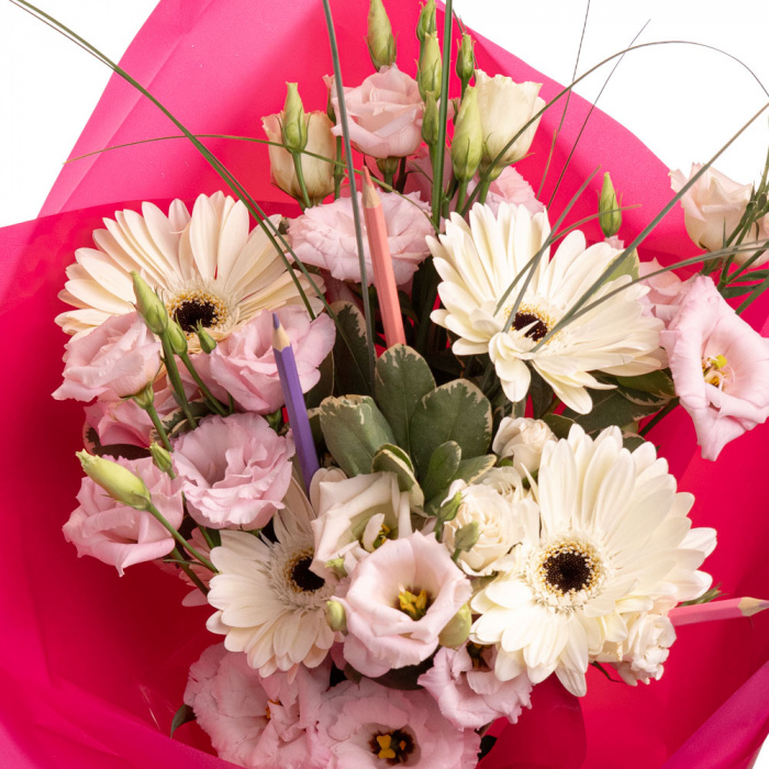 Detaliu de aproape cu florile din Buchet cu gerbera si creioane colorate Back to School, varianta Deluxe, compus din 4 gerbera, 3 creioane colorate, 5 fire de beargrass, 4 fire de lisianthus roz, 1 trandafir ramificat alb si 2 crengute de pittosporum