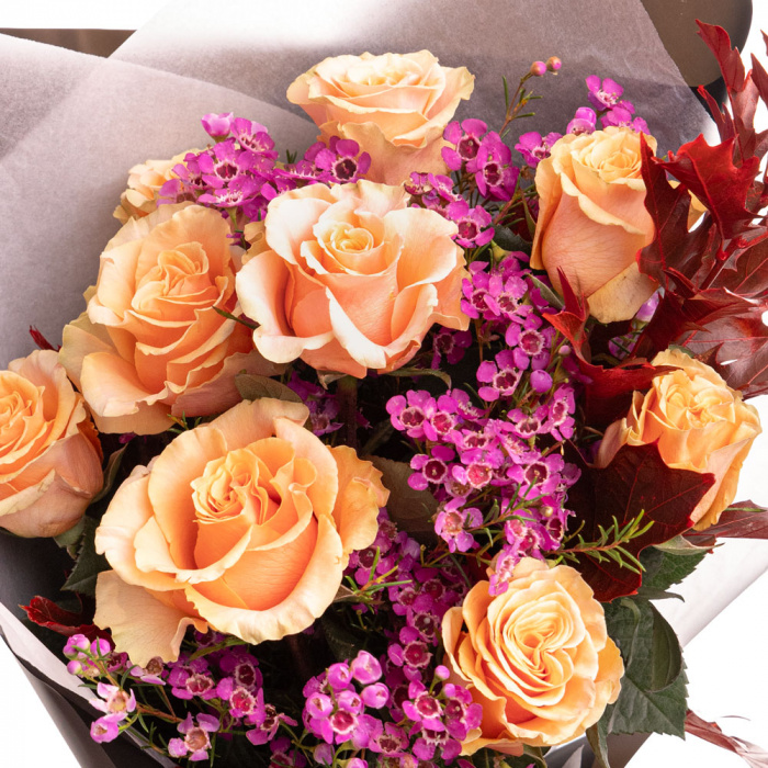 Detaliu de aproape cu florile din Buchet Autumn trandafiri portocalii, varianta Deluxe, compus din 9 trandafiri portocalii, 3 crengute de chamelaucium roz, 2 crengute de quercus
